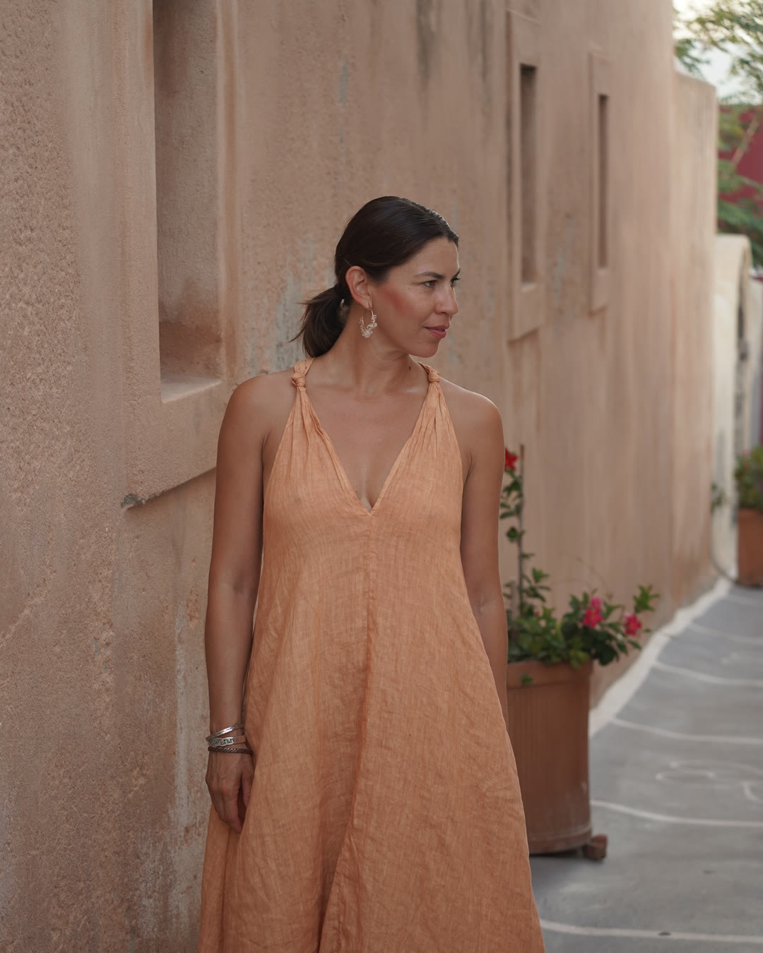 Gloria Quezada in a terracotta linen dress beside a sunlit wall