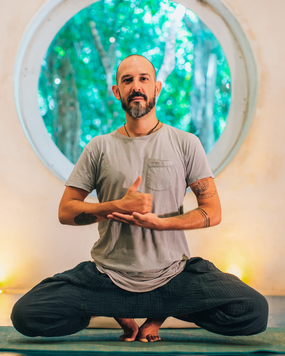 Pablo Jivam seated in a yoga posture beneath a round window