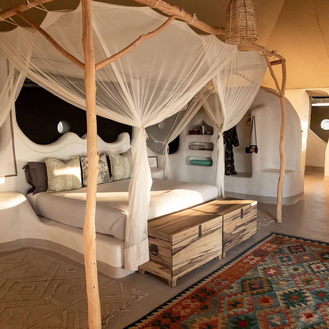 A Moela suite: the linen-draped bed with the bush through the open wall